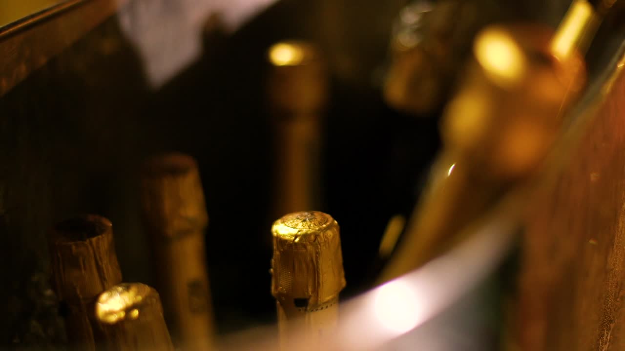 Bottiglie di champagne dorate in un secchiello di metallo pieno di ghiaccio.