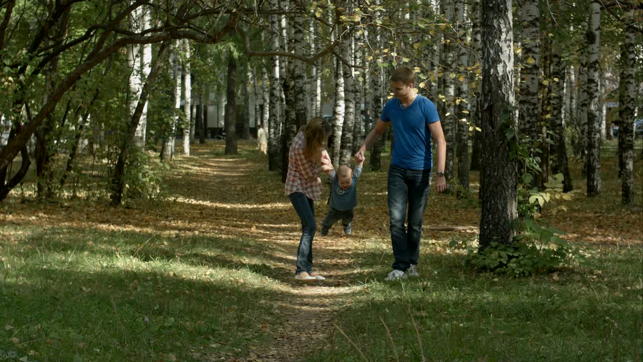 счастливая молодая семья веселится в осеннем парке на открытом воздухе в солнечный день.