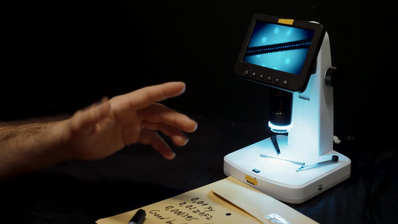A hand points to a microscope display showing magnified details, representing quality control, inspection, and precision in a laboratory or industrial setting