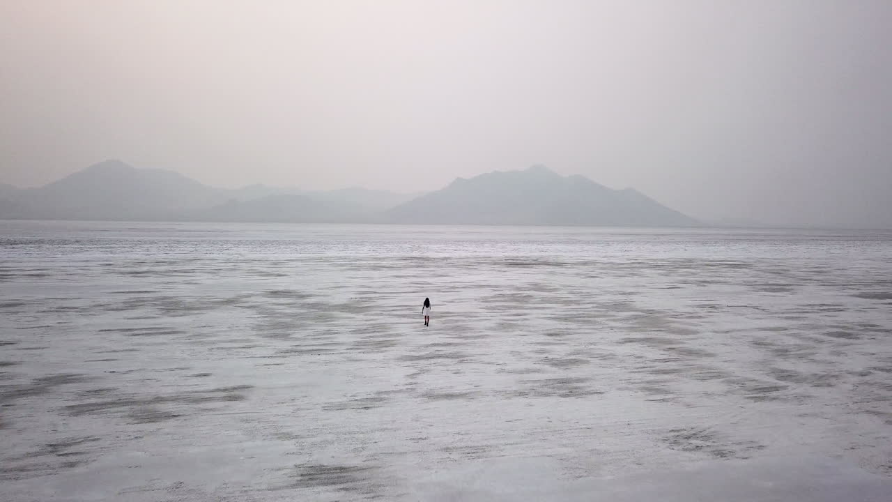 유타 사막 소금 평지를 걷는 여성의 극적인 공중 영상