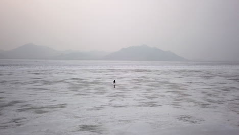 Dramatic-aerial-footage-of-woman-walking-in-Utah-desert-salt-flat