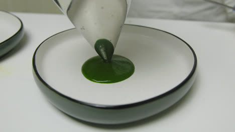 nozzle tip spinach puree pouring on ceramic plate