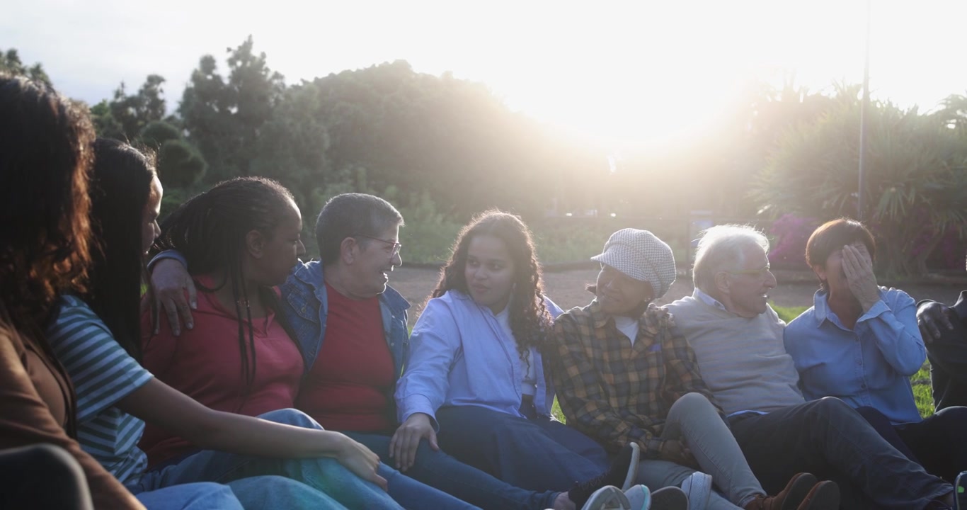Diverse Multi-Generational Group of Friends Talking and Laughing Outdoors at Sunset