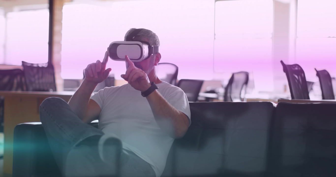 Animazione di scie luminose blu e rosa che si muovono su un uomo caucasico che indossa un visore VR in ufficio.
