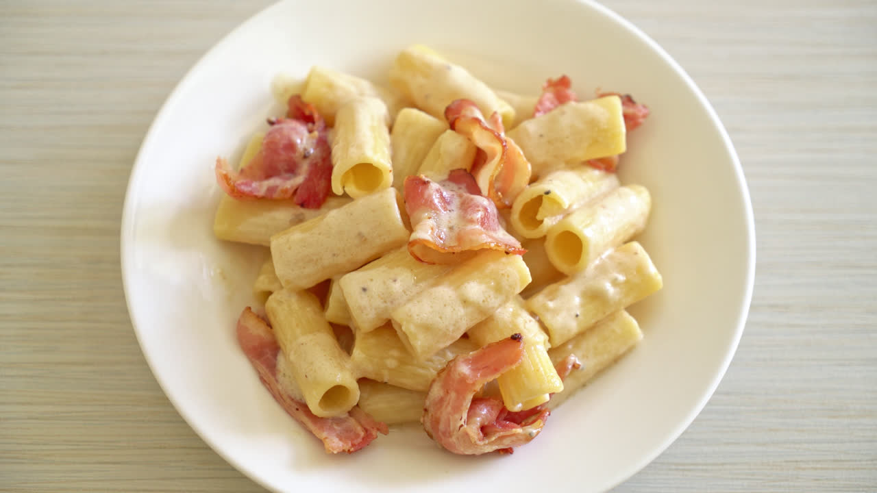 espaguetis rigatoni caseros con salsa blanca y tocino - estilo de comida italiana