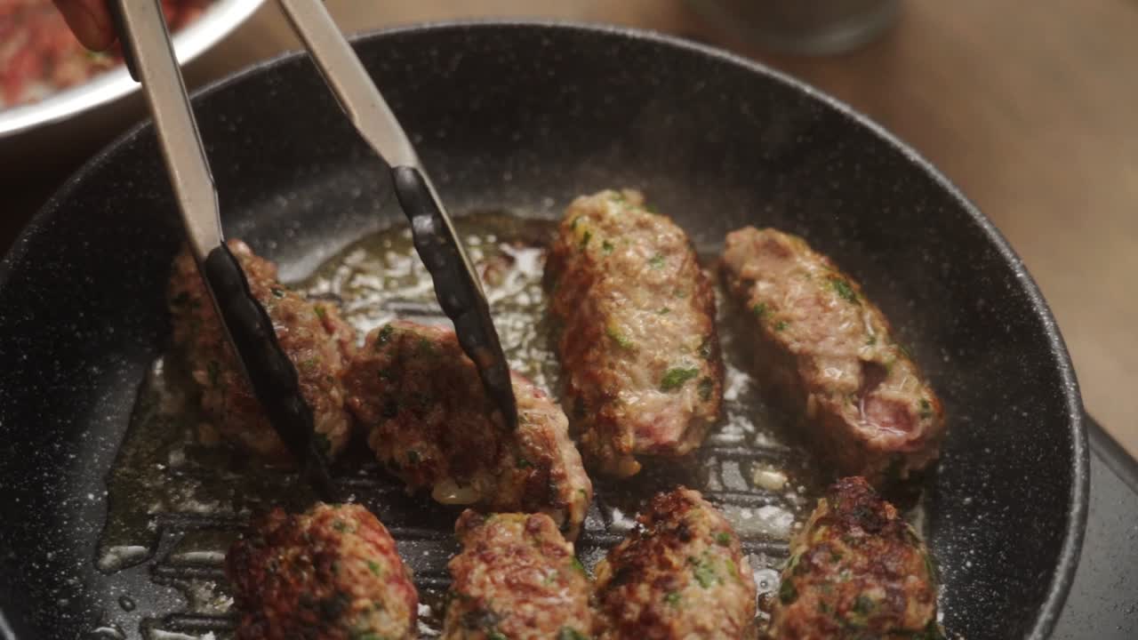 Cocinero irreconocible volteando Salisbury steaks en una sartén
