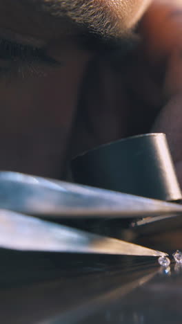 cu: professional jeweler examines shiny transparent gems through magnifying glass at wooden table extreme close view