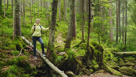 una mujer es una turista en el bosque descansa cerca del árbol admirando la hermosa vista vida activa