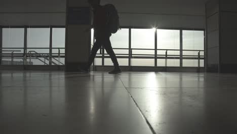 공항 홀을 걷는 여행자, 태양 플레어, 정적 샷, 낮은 각도