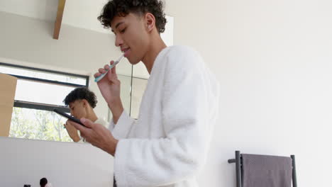 brushing teeth and using smartphone, person in bathrobe multitasking in bathroom