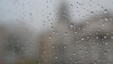 close-up view of raindrops on a window looking out to gloomy, overcast weather