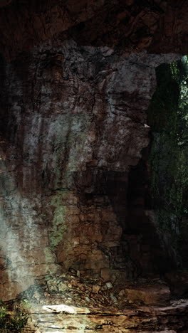 a dark cave entrance with light streaming in