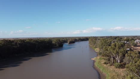 Vista-Aérea-De-Un-Río-Con-árboles-Muertos-En-Su-Pequeño-Pueblo-En-El-Lado-Derecho