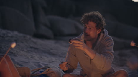 beach party at sunset with bonfire and roasting marshmellows with friends