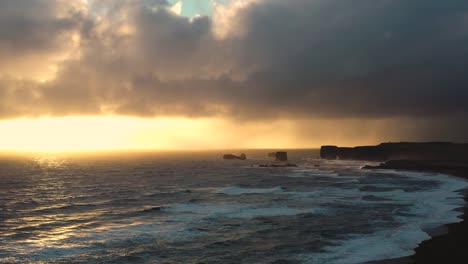 mesmerizing drone footage of iceland's black sand beach, featuring mighty waves against the sunset horizon