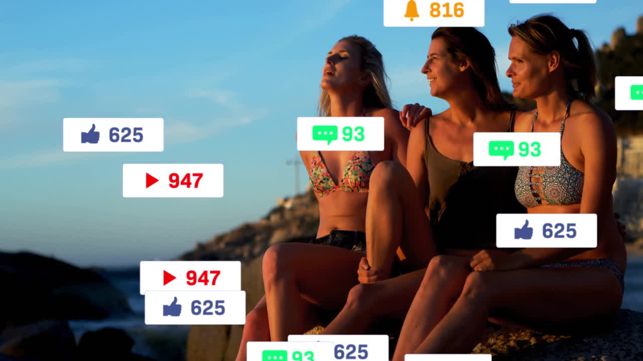Social media notifications animation over three women sitting by ocean