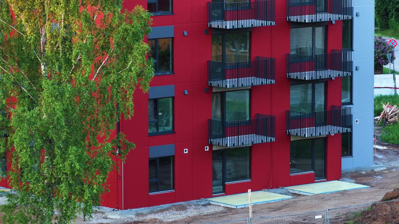 Moderno edificio residenziale rosso con balconi durante le fasi finali della sua costruzione