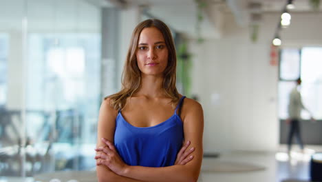 portrait of serious young businesswoman standing in busy modern open plan office