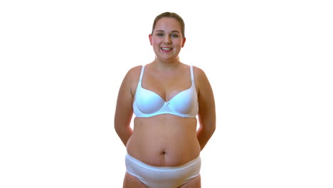 mujer gorda en ropa interior blanca se para con una sonrisa en el fondo blanco