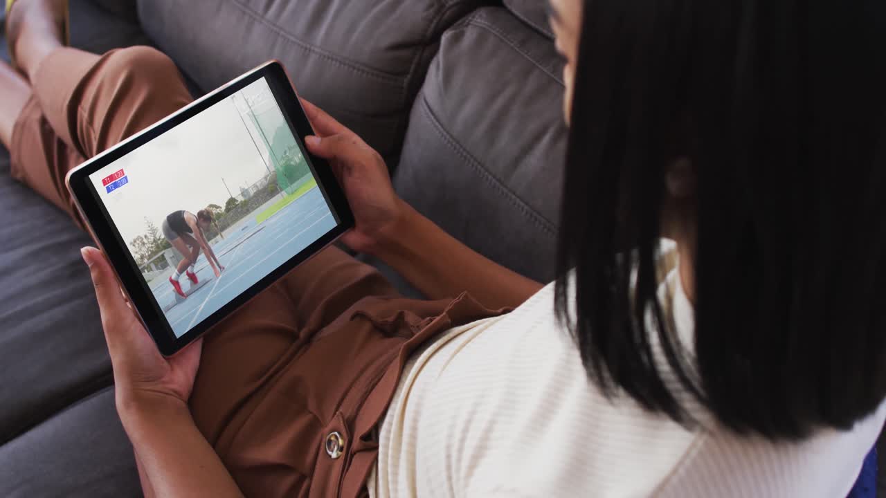 Composite of woman sitting at home on couch watching athletics running event on tablet