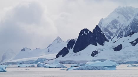 Paisaje-De-Montañas-Antárticas-Al-Atardecer,-Hermoso-Paisaje-Y-Nubes-Dramáticas-Y-Cielo-Con-Picos-Montañosos-E-Icebergs,-Calentamiento-Global-Y-Cambio-Climático-En-La-Península-Antártica-Con-Agua-De-Mar-Oceánica