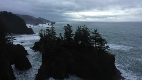 Excelente-Toma-Aérea-De-Pinos-En-Grandes-Rocas-Frente-A-La-Costa-De-Oregon-En-Un-Día-Nublado