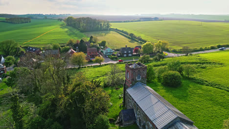 drone footage exhibits burwell village, once a medieval market town, with rural fields, old red brick homes, and the defunct saint michael parish church atop the wold hills in lincolnshire