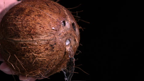 Water-leaking-out-of-coconut-on-black-background