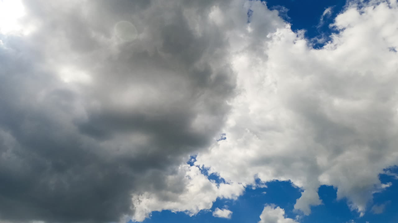 Floating soft clouds in the beautiful summer sky. Bright sun lights the horizon and fluffy clouds. Low angle view. Timelapse.