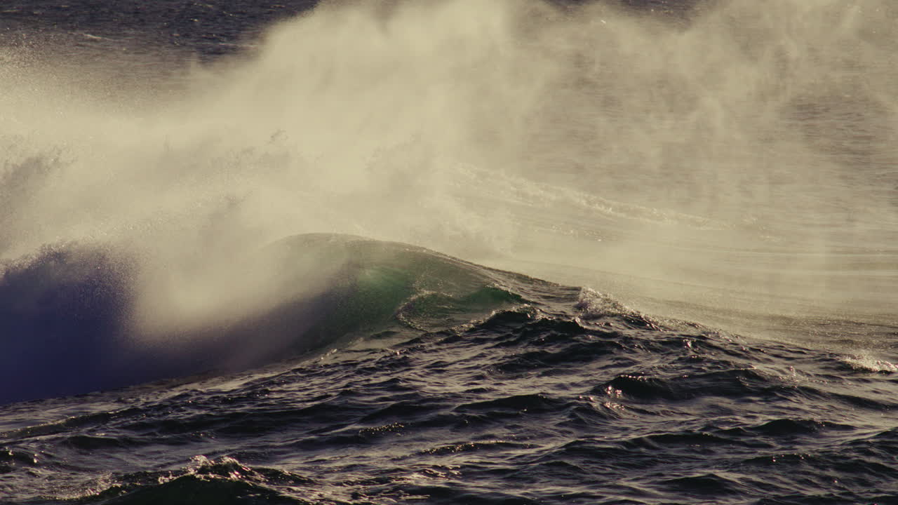Massive wave crashes with white spray under dramatic lighting, slow motion impact moment