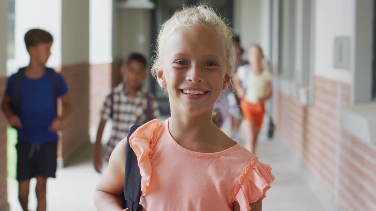 Video of happy caucasian girl standing at school corridor