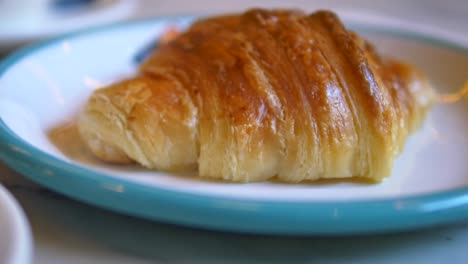 primer plano de un croissant dorado en un plato blanco