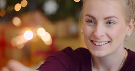 smiling young woman looking at sparkler 1