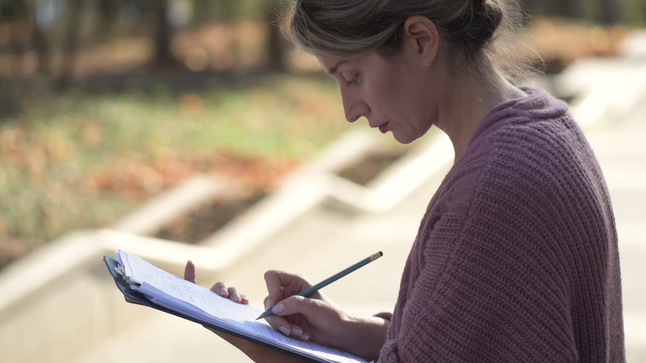 Woman sketching on a bench in the park on a sunny day