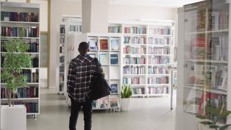 man standing in a library looking at bookshelves