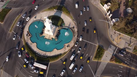 Aerial-orbit-shot-of-crowded-roundabout-with-monument-and-fountain-in-middle---Buenos-Aires,Argentina