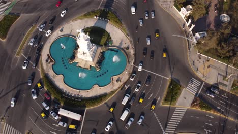 toma de órbita aérea de rotonda llena de gente con monumento y fuente en medio - buenos aires, argentina