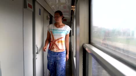 a woman walks by the train car and enters the compartment