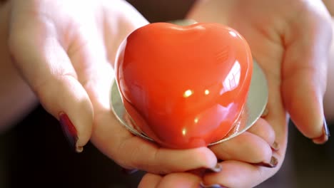 heart-shaped red cake in hands