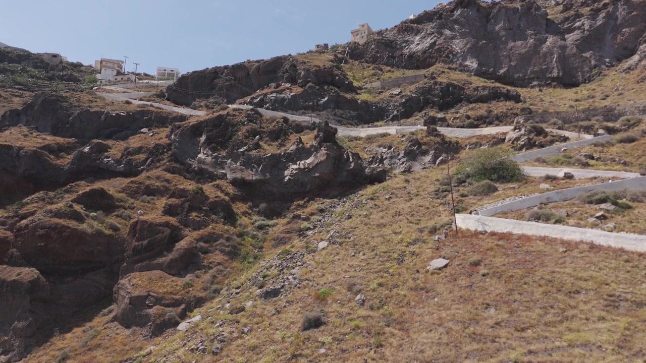 Ripresa aerea con drone che rivela una strada tortuosa sulle colline aride dell'isola di Thirasia a Santorini.