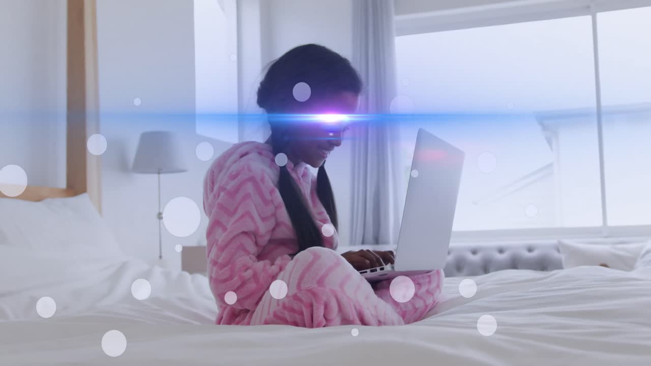 노트북을 사용하는 아프리카계 미국인 소녀 위의 빛의 반점과 흔적의 애니메이션