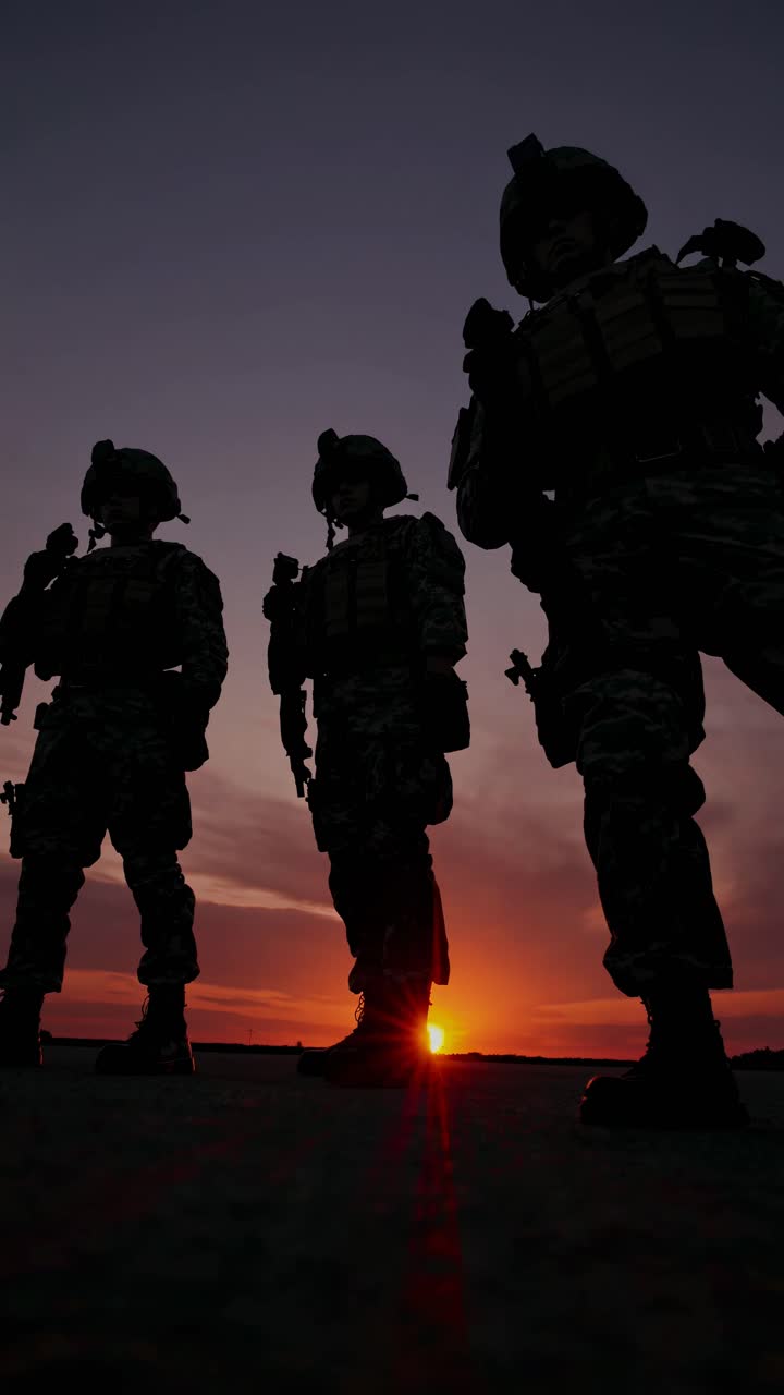Silhouetted soldiers in tactical gear at sunset, captured from a low-angle, creating a dramatic