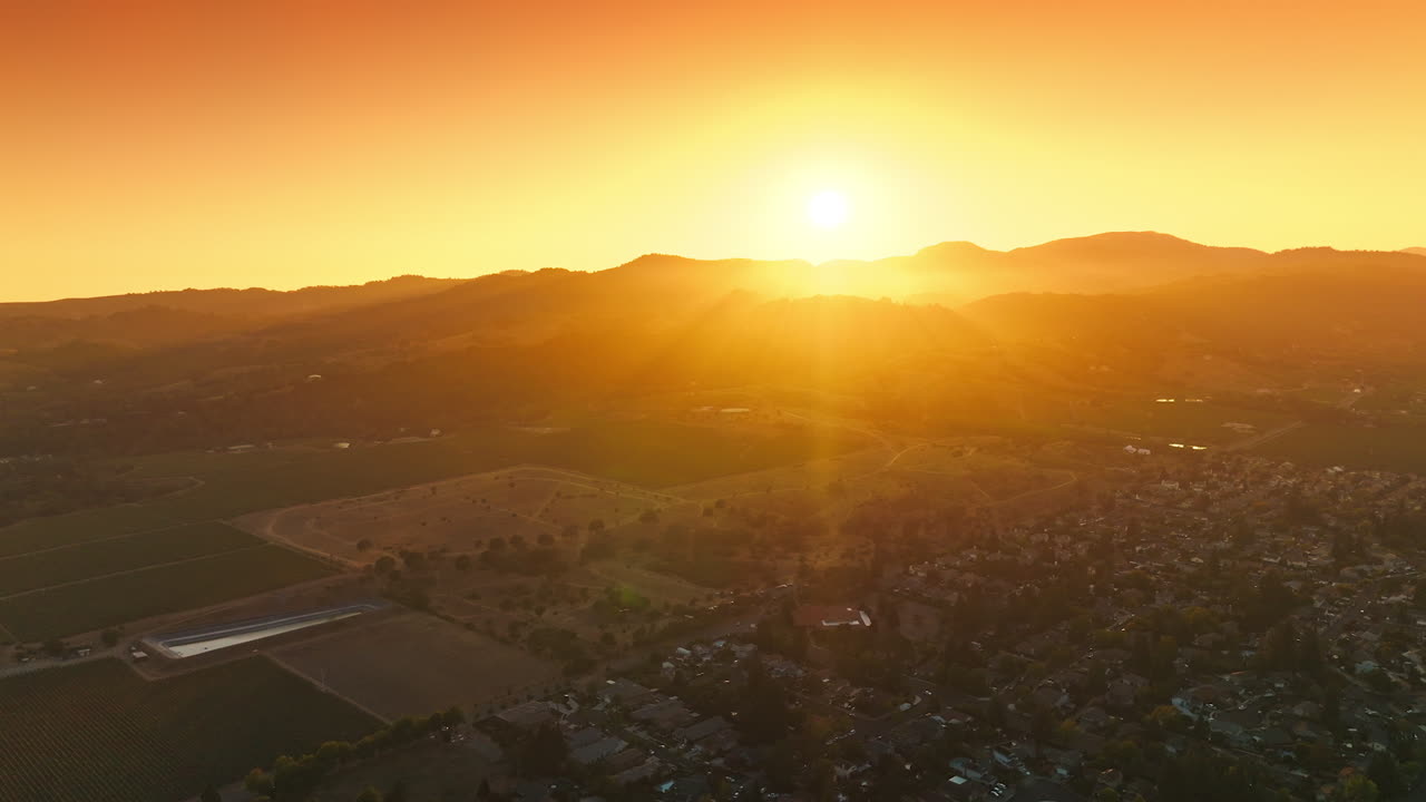 Bright sun setting behind the mountains. Beautiful valley of Napa with lots of cozy houses. Aerial view.