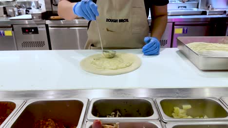 chef prepares pizza dough with toppings