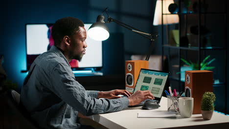 black accountant working on monthly revenue balance on laptop at home