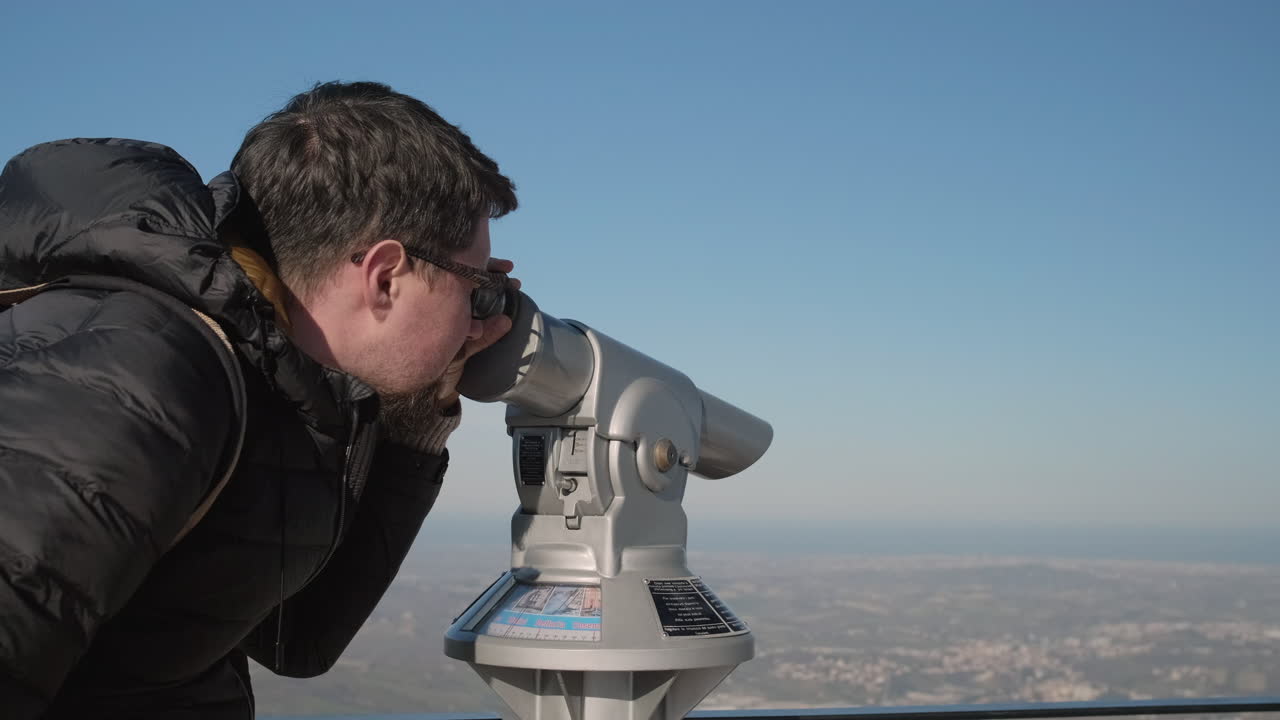 hombre usando binoculares en la cima de una montaña