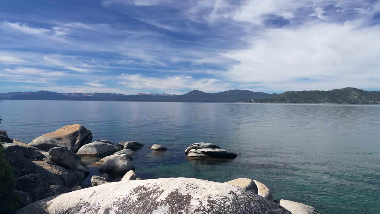 Granitblokke hviler i det klare vand i Lake Tahoe under en bred bjerghorisont
