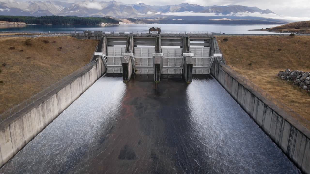 Water exiting hydroelectricity dam at Lake Pukaki, mountains in background