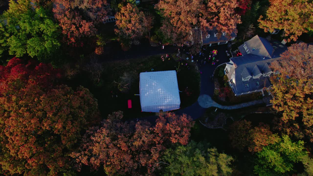 Halloween neighborhood gathering with an inflatable tent surrounded by colorful fall trees.