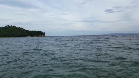 High-Speed,-Aerial,-Establishing-shot-of-Surface-of-Vast-Ocean-with-Buoy-Flag-in-Catanduanes,-Philippines